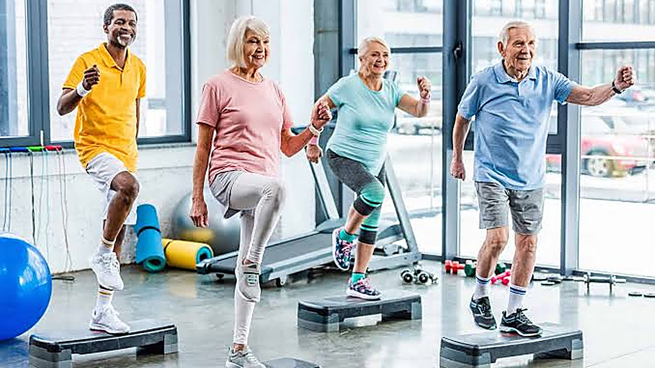 Group of older adults exercising on step platforms in a gym class